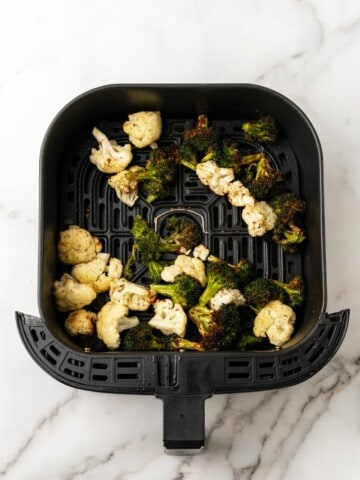 Cooked broccoli and cauliflower in air fryer basket