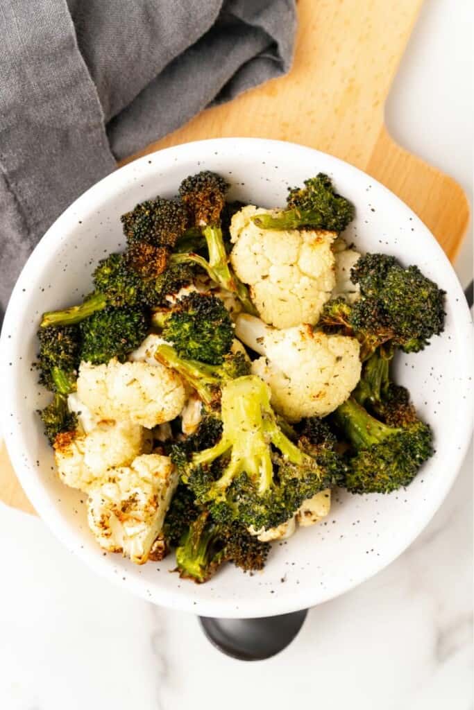 Broccoli and Cauliflower prepared in the air fryer, served in a white bowl.