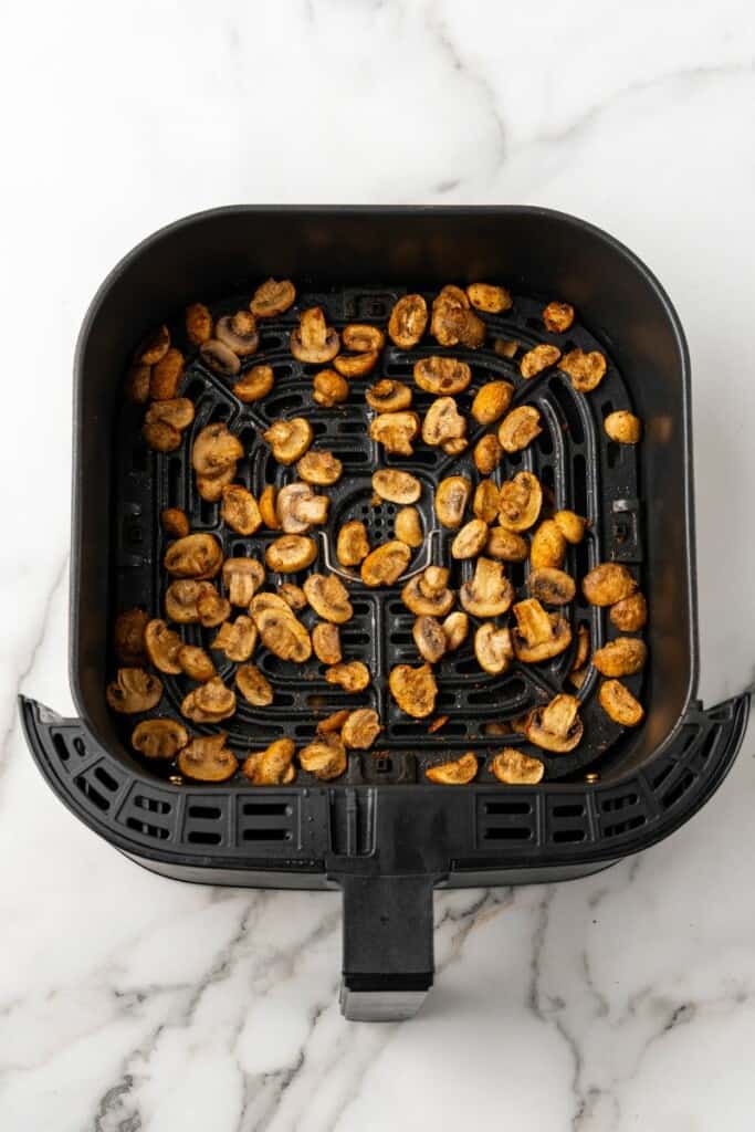 Air Fried Mushrooms resting in a black air fryer basket.