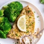 Air Fryer Swordfish on a white plate topped with lemon, served with broccoli.