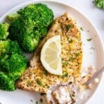 Air Fryer Swordfish on a white plate topped with lemon, served with broccoli.