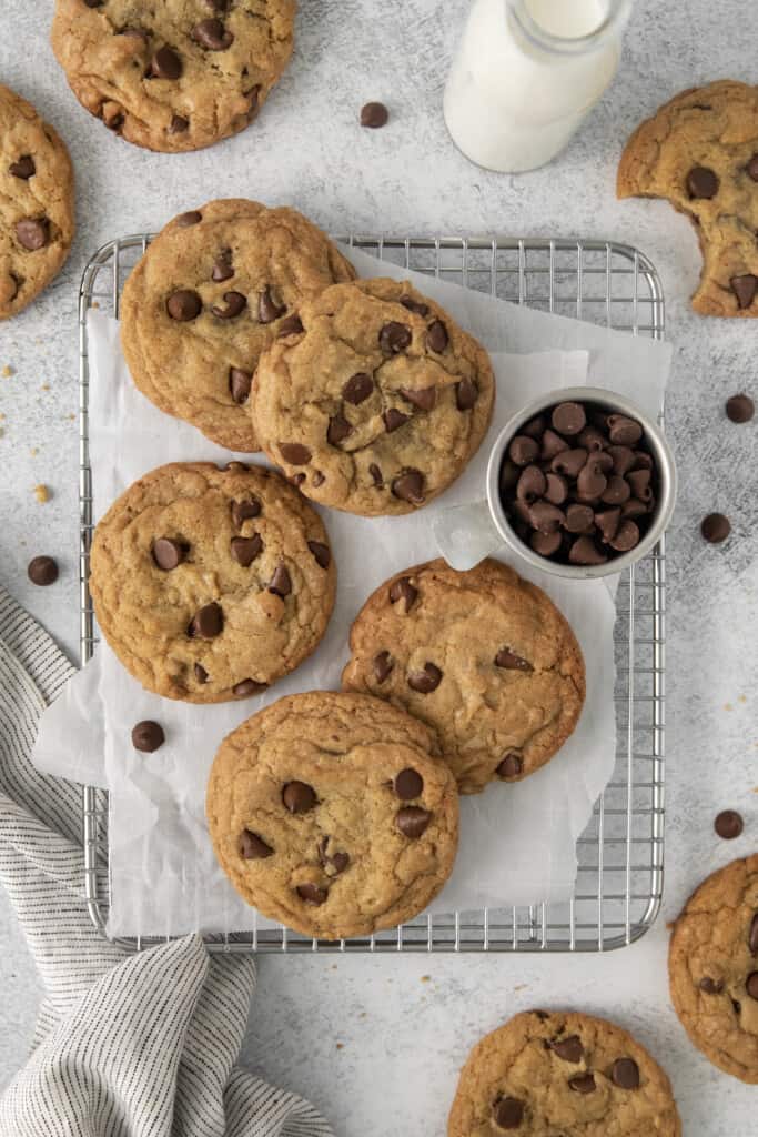 Chocolate Chip Cookies lying flat on a cooling rack with a sheet of parchment paper beneath them.