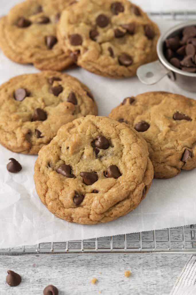 Baked chocolate chip cookies placed on a cooling rack lined with parchment paper.