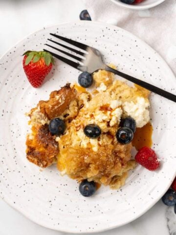 Overhead view of Crockpot French Toast Casserole on a white plate with berries and a fork.