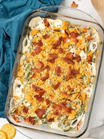 Baked Green Bean Casserole in a clear 9x13 baking dish with crushed bacon sprinkled on top.
