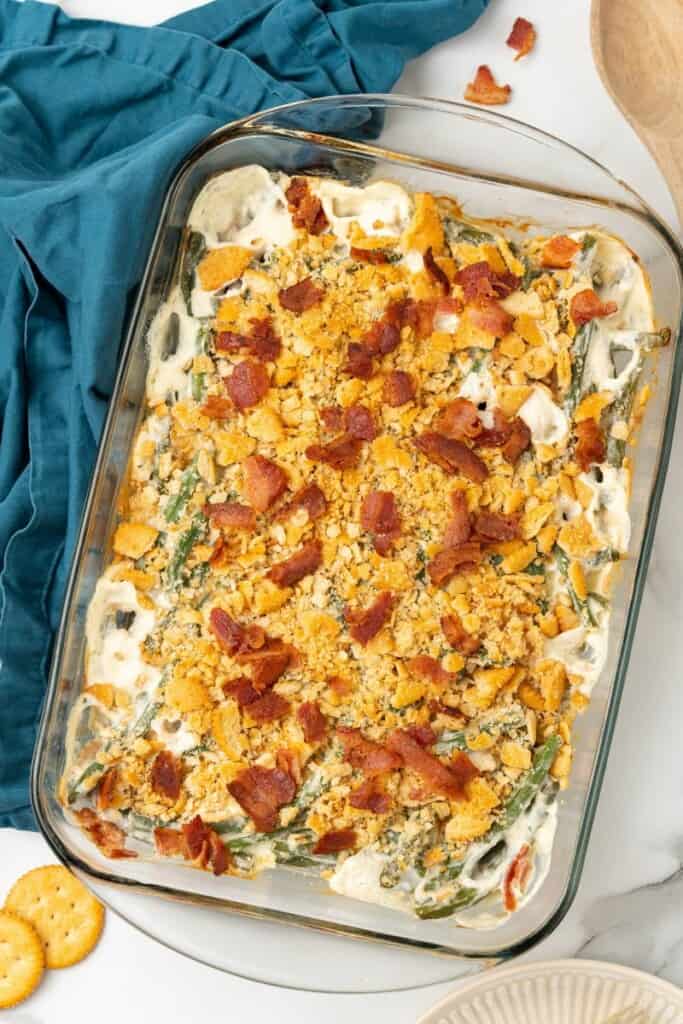 Baked Green Bean Casserole in a clear 9x13 baking dish with crushed bacon sprinkled on top.