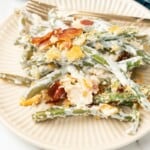 A serving of Green Bean Casserole with Cream Cheese on an off white plate.