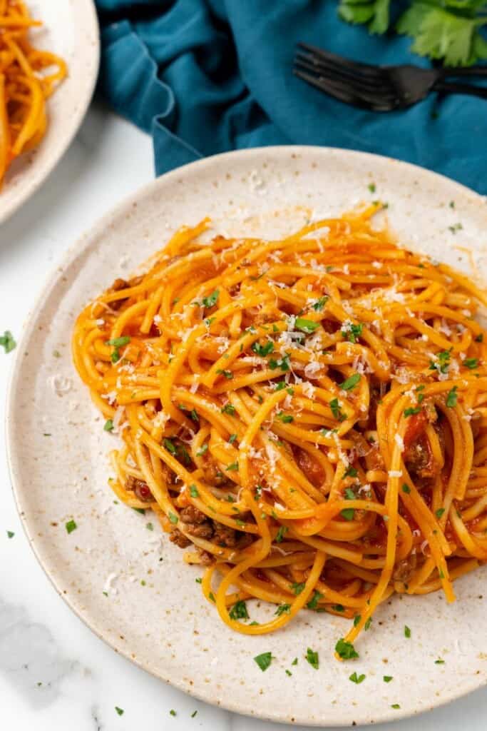 Overhead view of spaghetti on an off white plate.