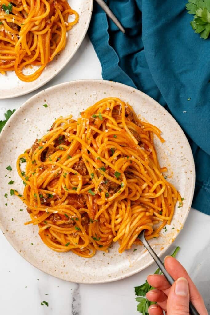 Spaghetti prepared in a Ninja Foodi served on an off white plate.