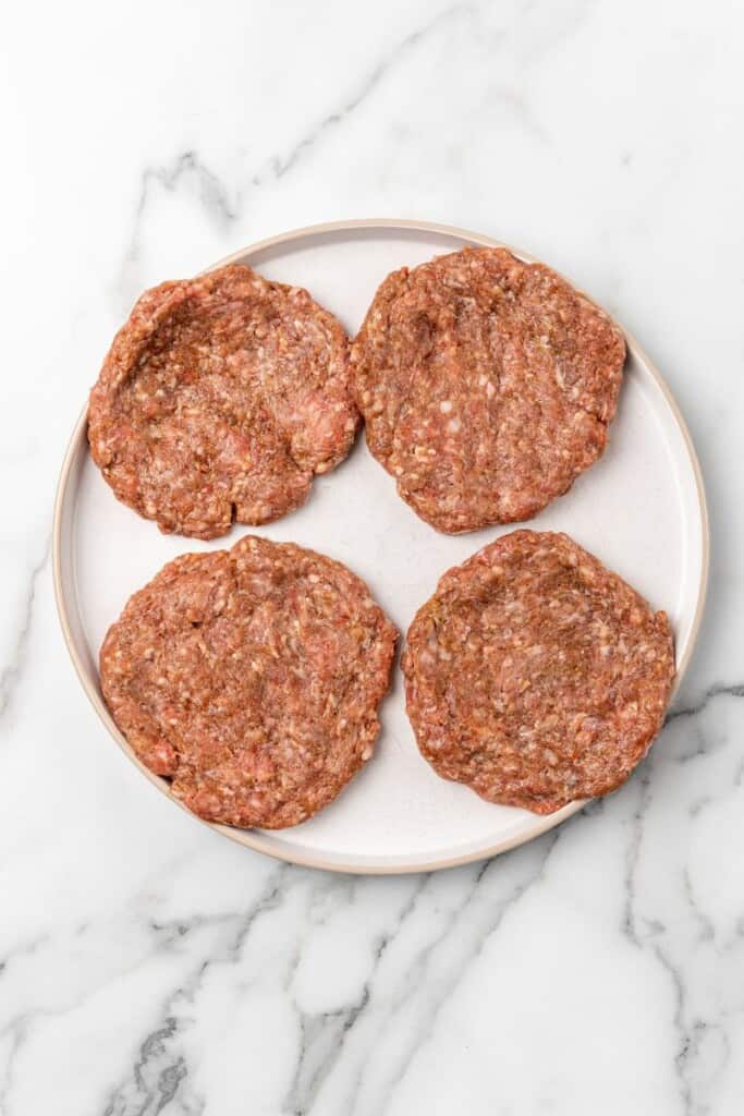 Overhead view of four hamburgers ready to be cooked in a Ninja Foodi.