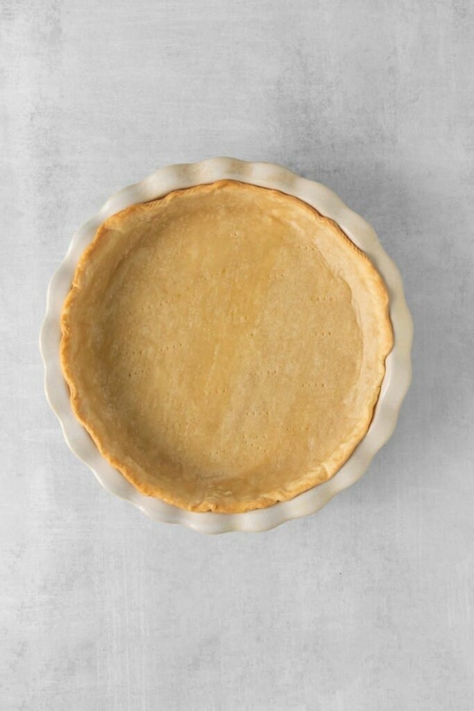 Overhead view of par-baked pie crust in a pie dish.