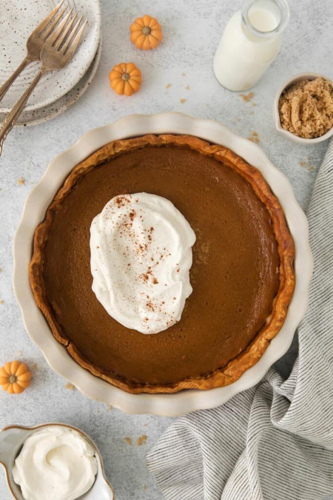Overhead view of baked pumpkin pie with whipped cream on top.