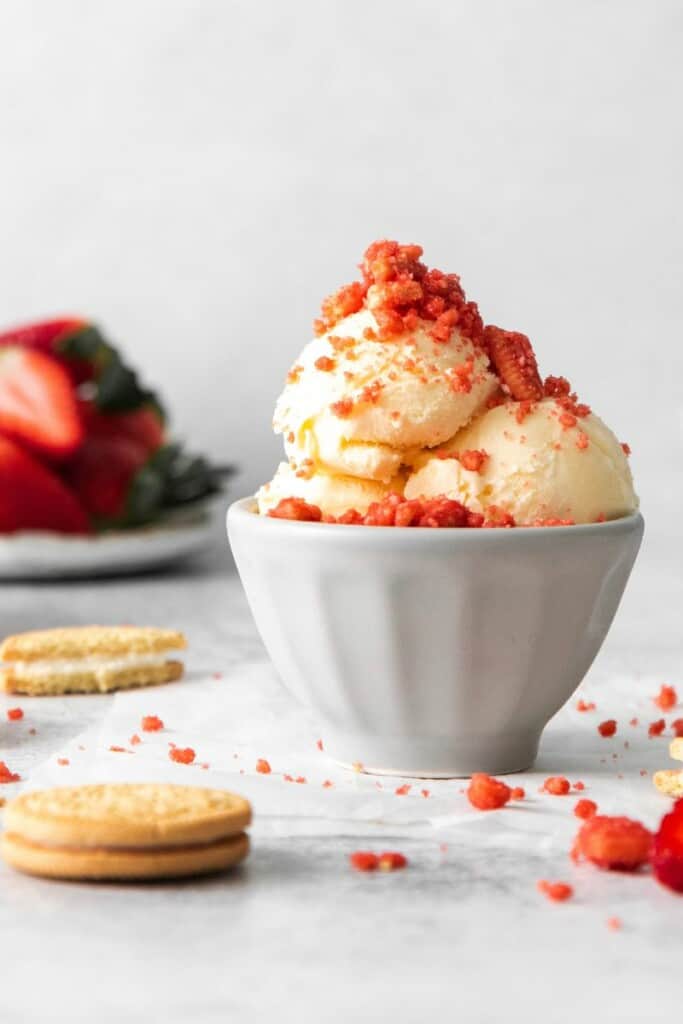 Strawberry Crunch Topping on vanilla ice cream in an off white bowl.