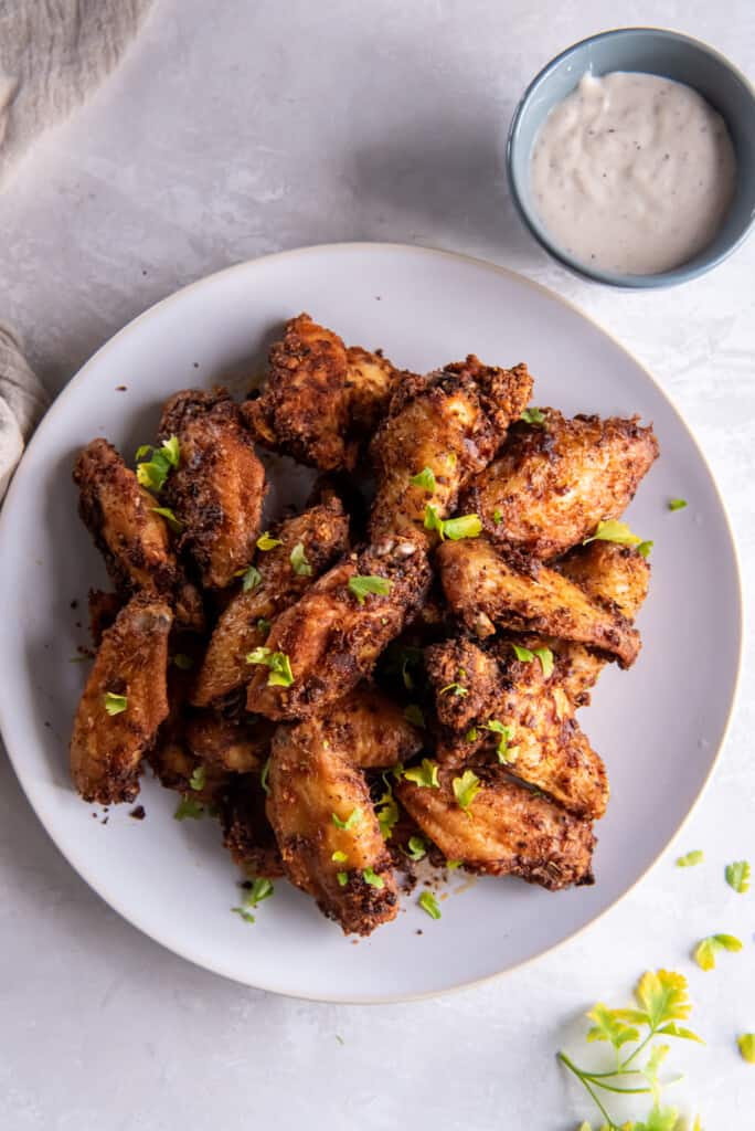 Overhead view of chicken wings prepared in the air fryer on a white plate.
