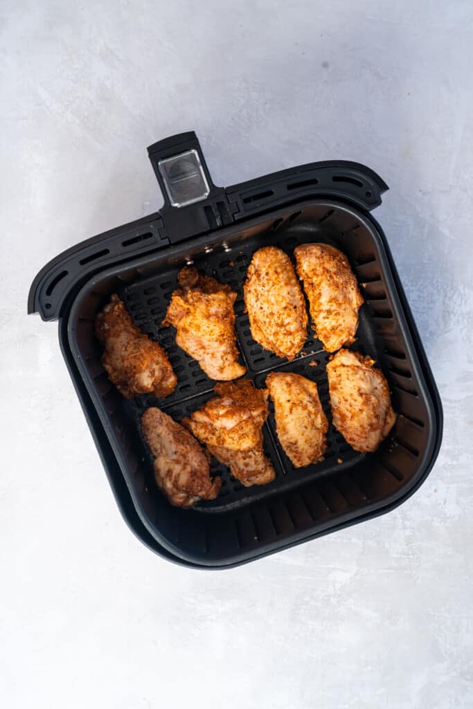 Overhead view of chicken wings in an air fryer basket.