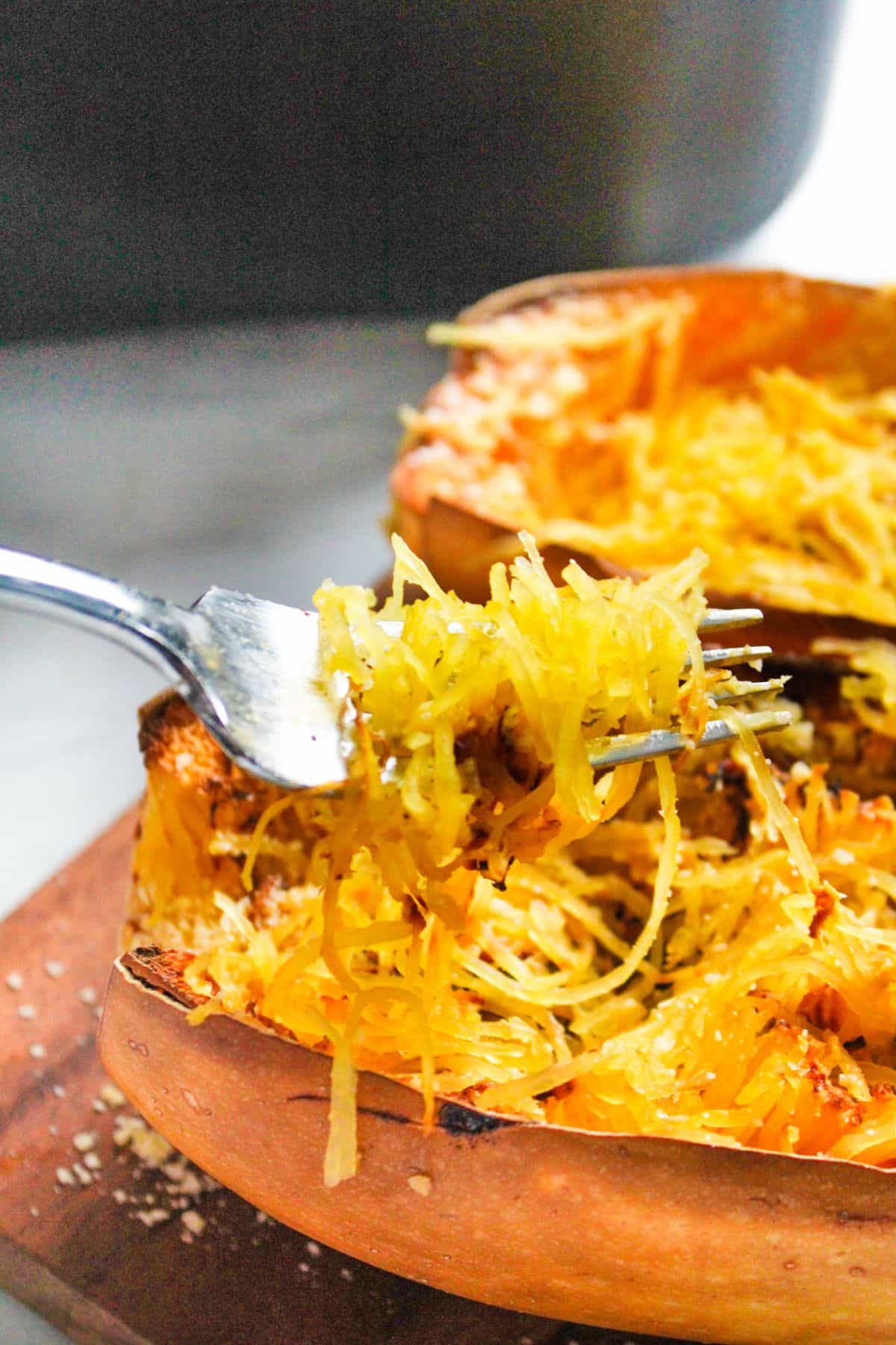 Fork pulling out spaghetti squash stands from the half of squash.