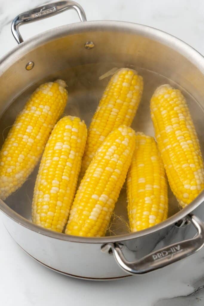 Corn on the cob being boiled in a large pot.