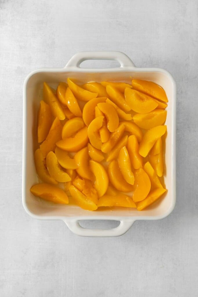 Peaches in a square white baking dish.