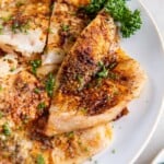 A closeup view of an air fried piece of flounder on a white plate.