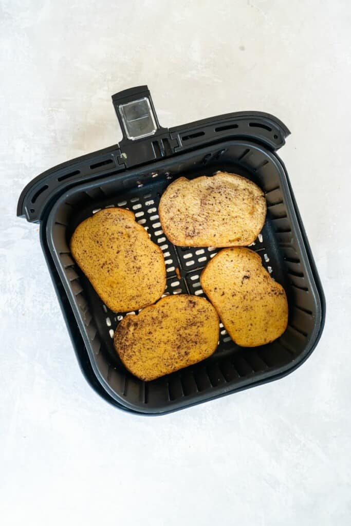 Four slices of french toast in a black air fryer basket.