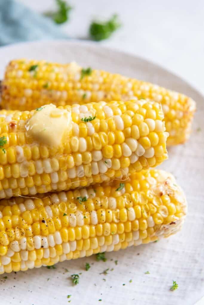 Close up view of corn prepared in the air fryer with a pat of butter on top.