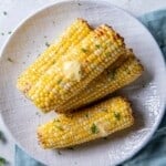 Overhead view of four ears of corn that have been prepared in the air fryer.