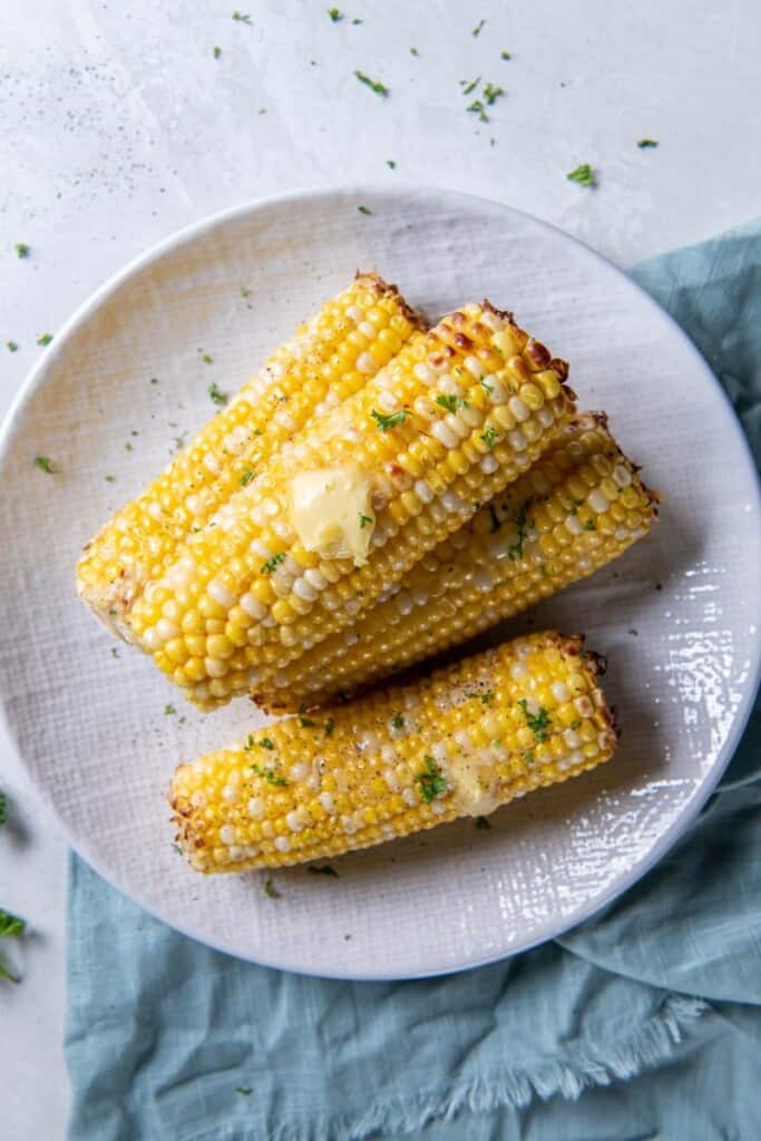 Overhead view of four ears of corn that have been prepared in the air fryer.