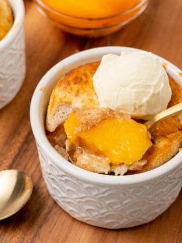 An individual serving of peach cobbler in a small white dessert dish.