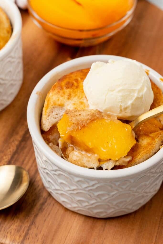 An individual serving of peach cobbler in a small white dessert dish.