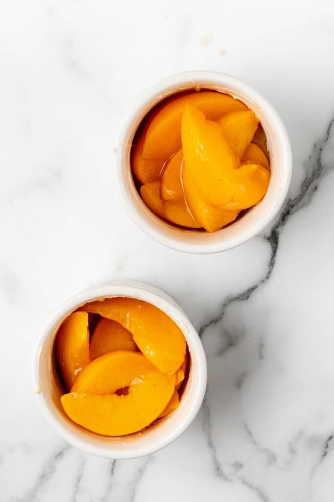 Seasoned peaches divided into ramekins.