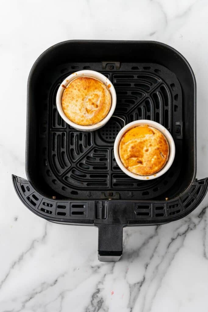 Fully cooked peach cobblers in a black air fryer basket.