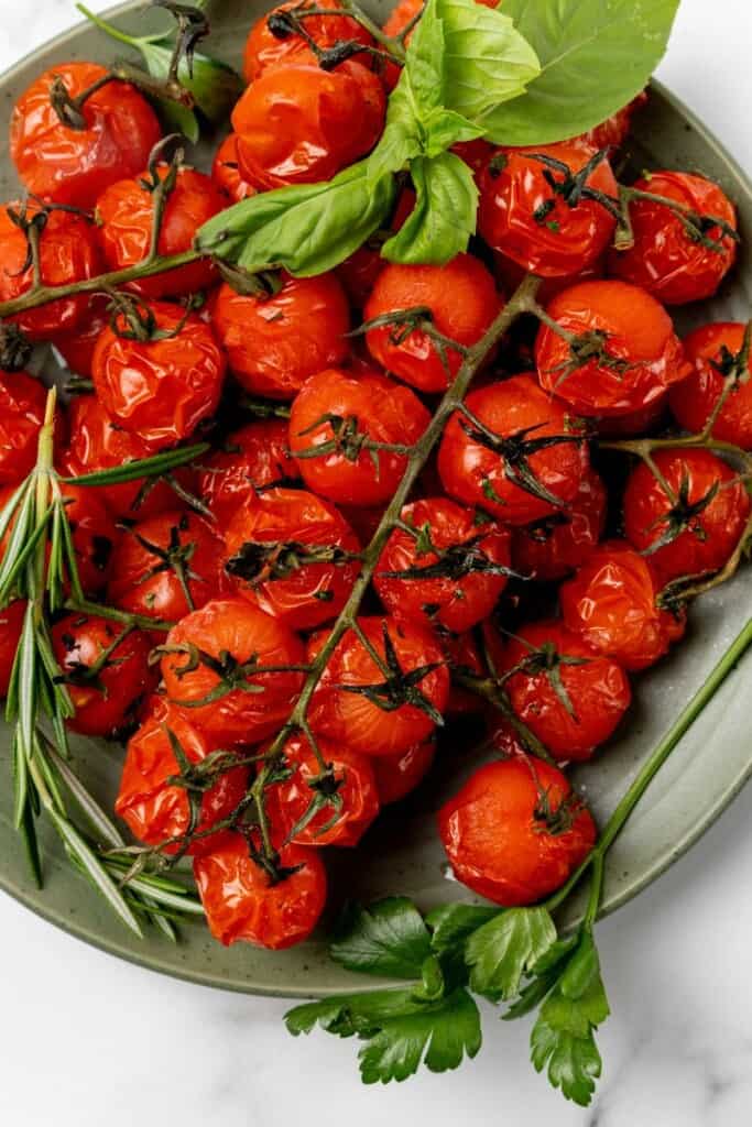 Seasoned air fried cherry tomatoes resting on a green serving plate.