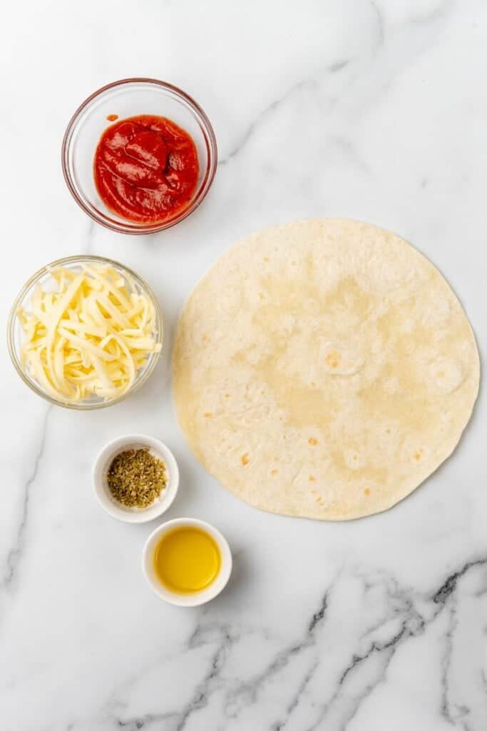 Overhead view of ingredients needed to prepare an air fryer tortilla pizza.