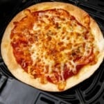 Tortilla pizza prepared in an air fryer resting in a black basket.