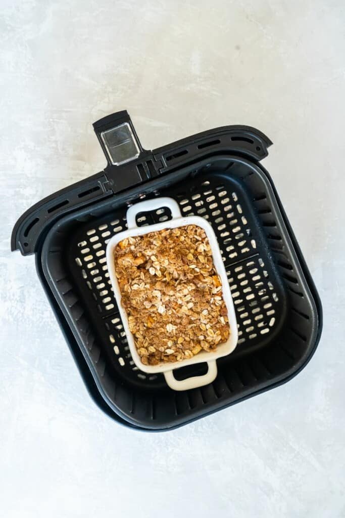 Air Fried Apple Crisp in a white baking dish resting in a black air fryer baset. 