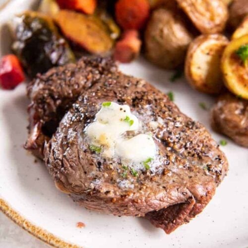 Air Fried Filet Mignon on a white plate with melted butter, served with mixed vegetables.