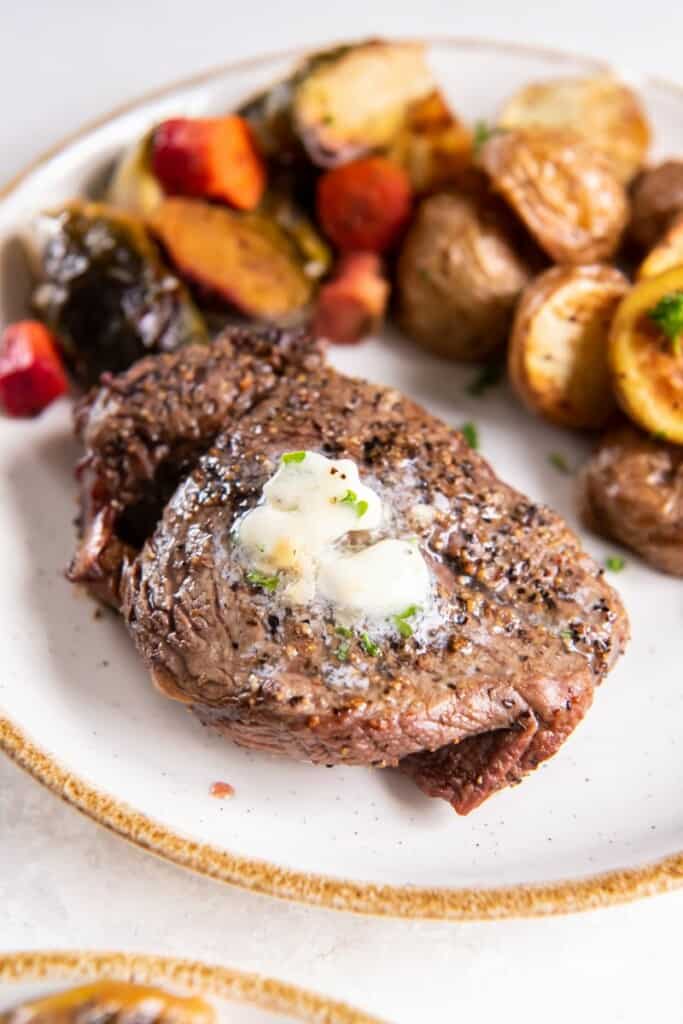 Air Fried Filet Mignon on a white plate with melted butter, served with mixed vegetables.