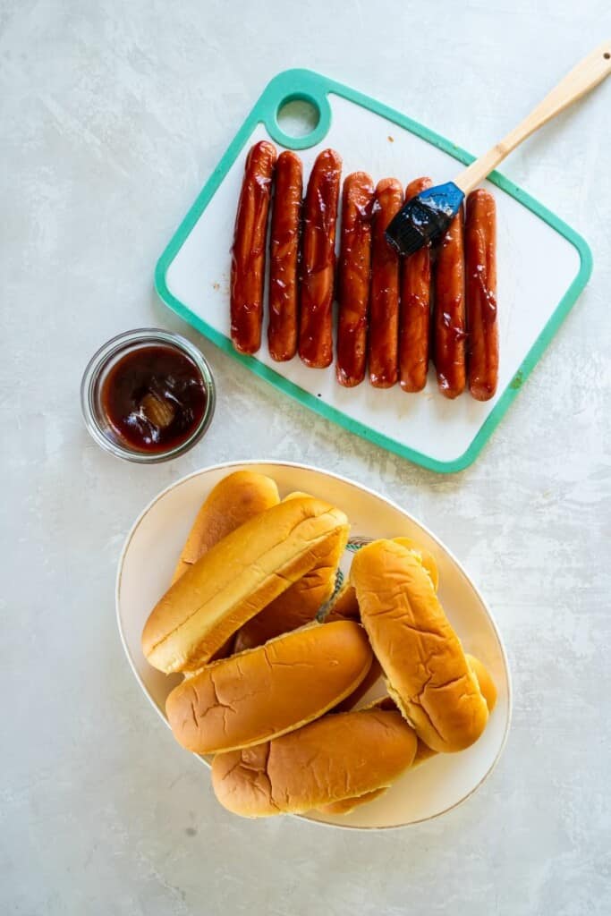 Brushing bbq sauce on hot dogs before grilling.