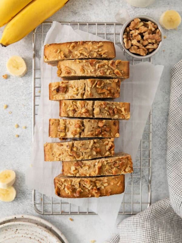 Loaf of banana bread cut into slices on a cooling rack.