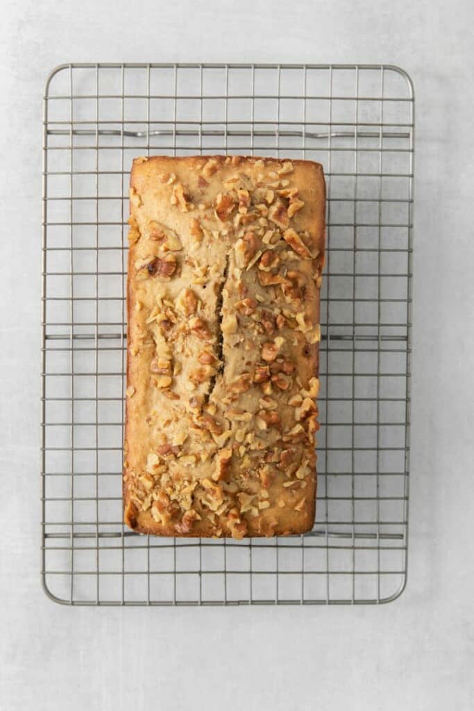 Loaf of baked banana bread resting on a cooling rack.