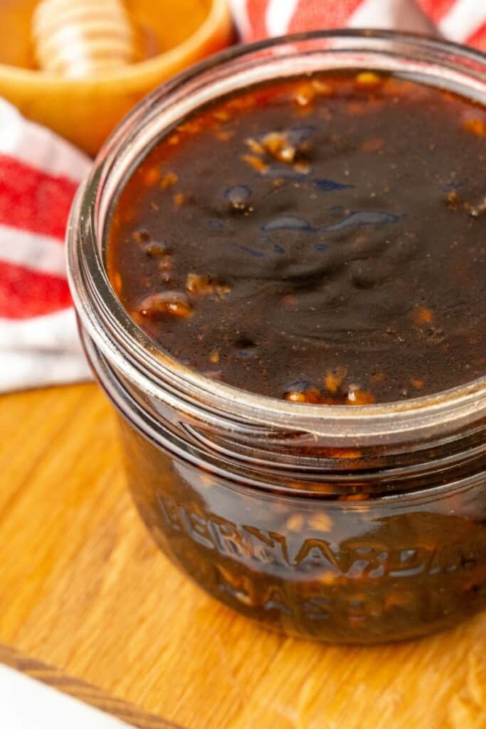 Closeup view of honey garlic sauce in a clear small mason jar.