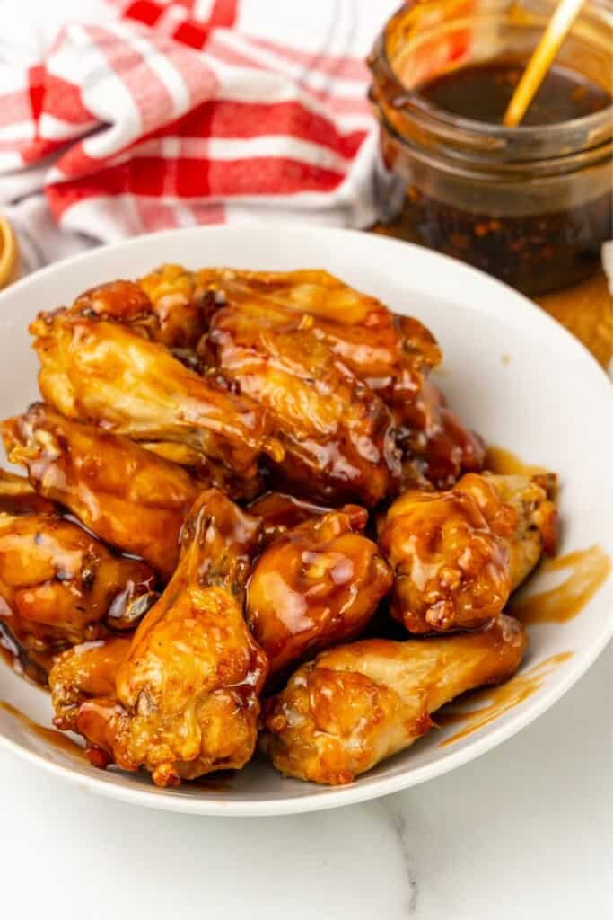 Honey Garlic Sauce coating chicken wings resting on a white plate.