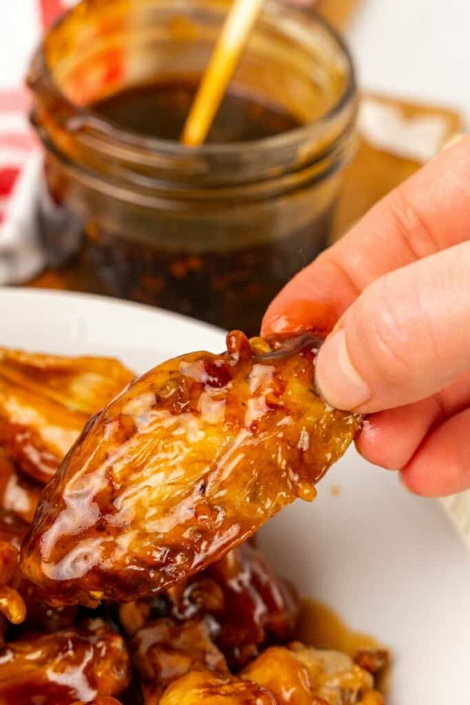 Close up view of a honey garlic sauce coated chicken wing.