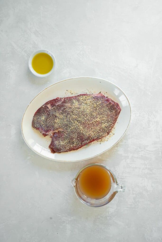 Seasoning flank steak to prepare it to be cooked.