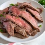 Slices of flank steak on a white plate.