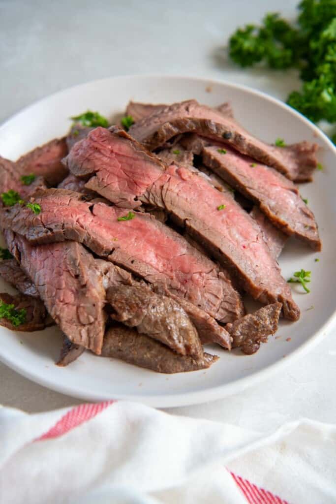 Slices of flank steak on a white plate.