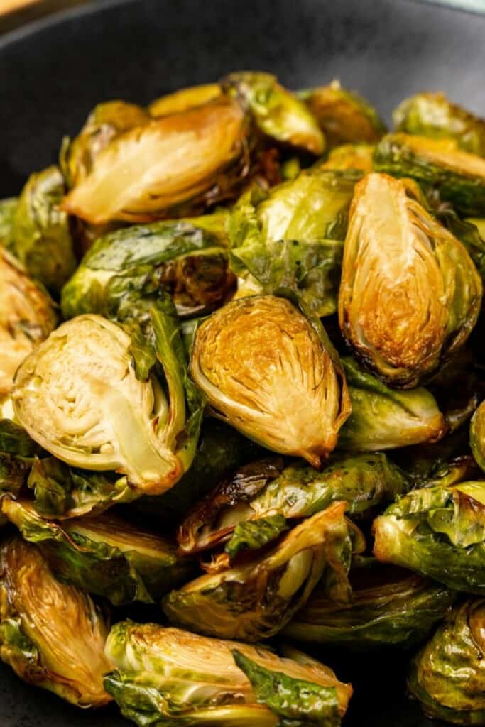 Closeup view of brussels sprouts resting in a black bowl.