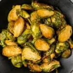 Brussels Sprouts prepared in the air fryer resting in a black bowl.