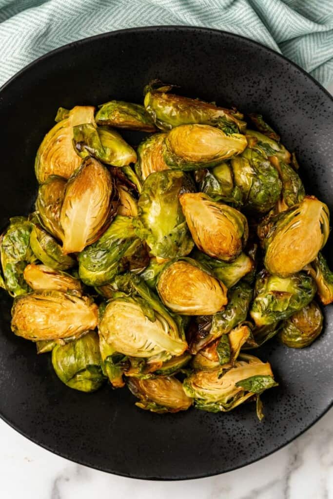 Brussels Sprouts prepared in the air fryer resting in a black bowl.