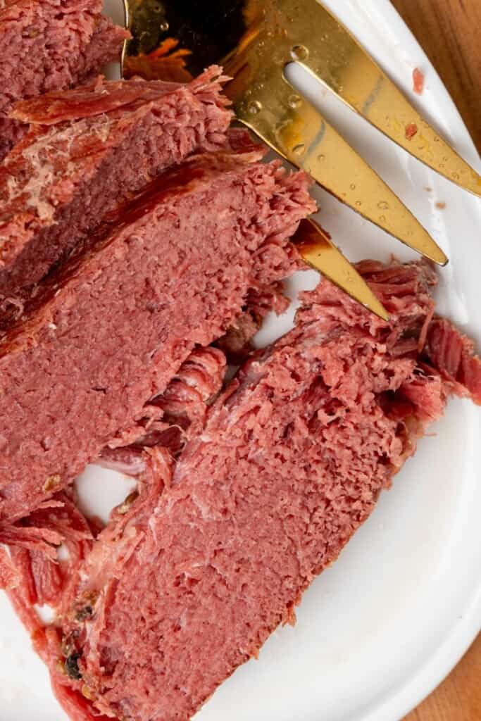 Close up view of a slice of corned beef brisket on a white plate.